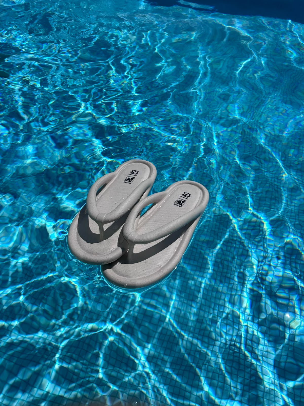 Sandalias W150 color beige junto a una alberca